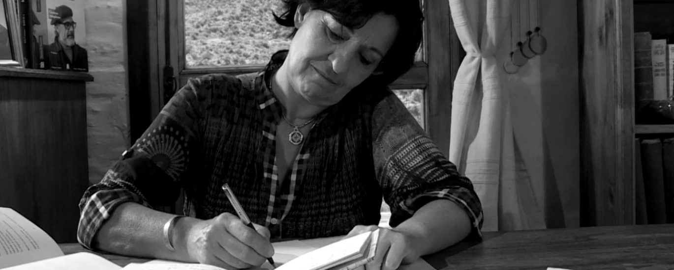 Liliana Bodoc, escritora argentina, rodeada de libros y sonriendo.